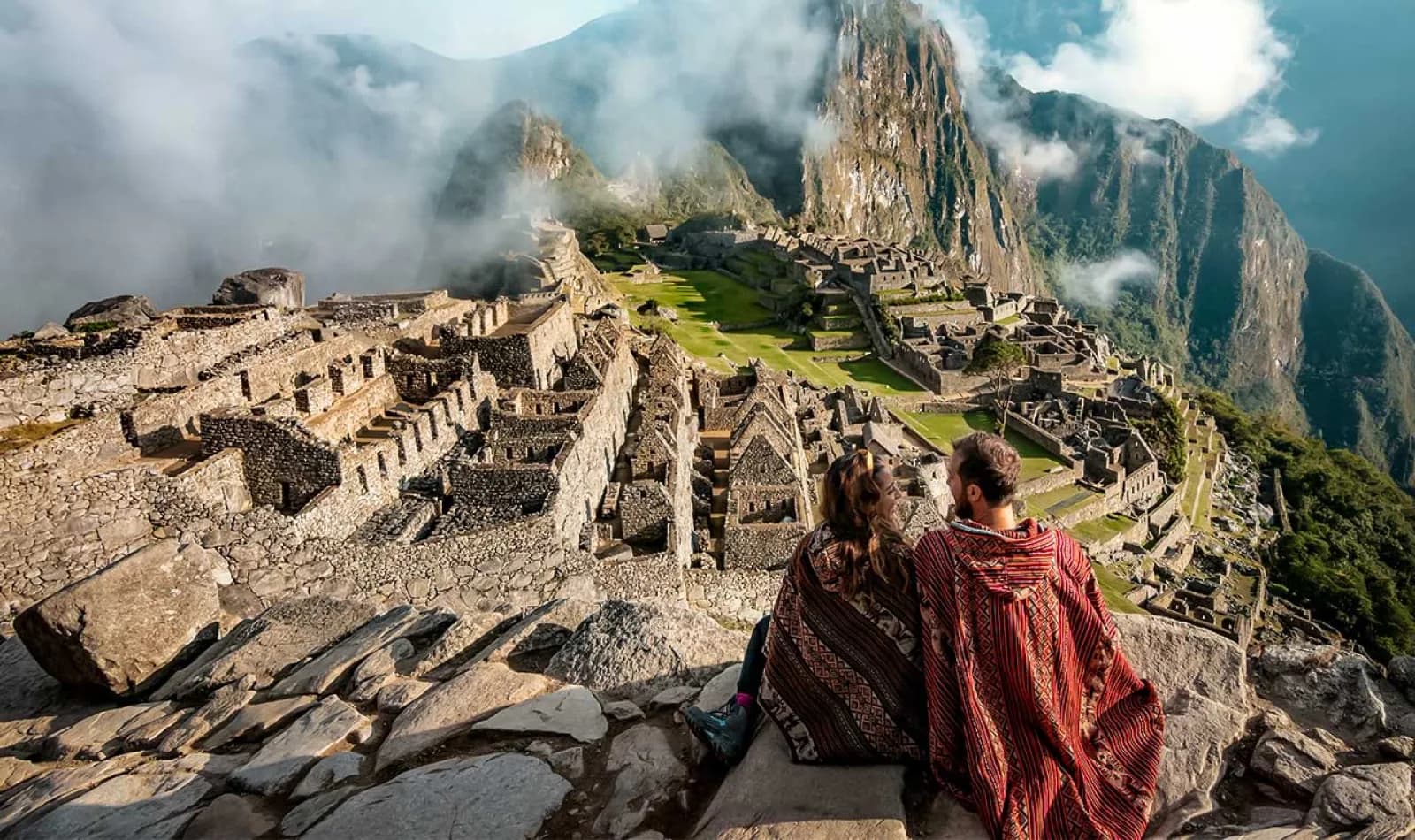 Senederistas sentados, observando el santuario inca de Machu Picchu
