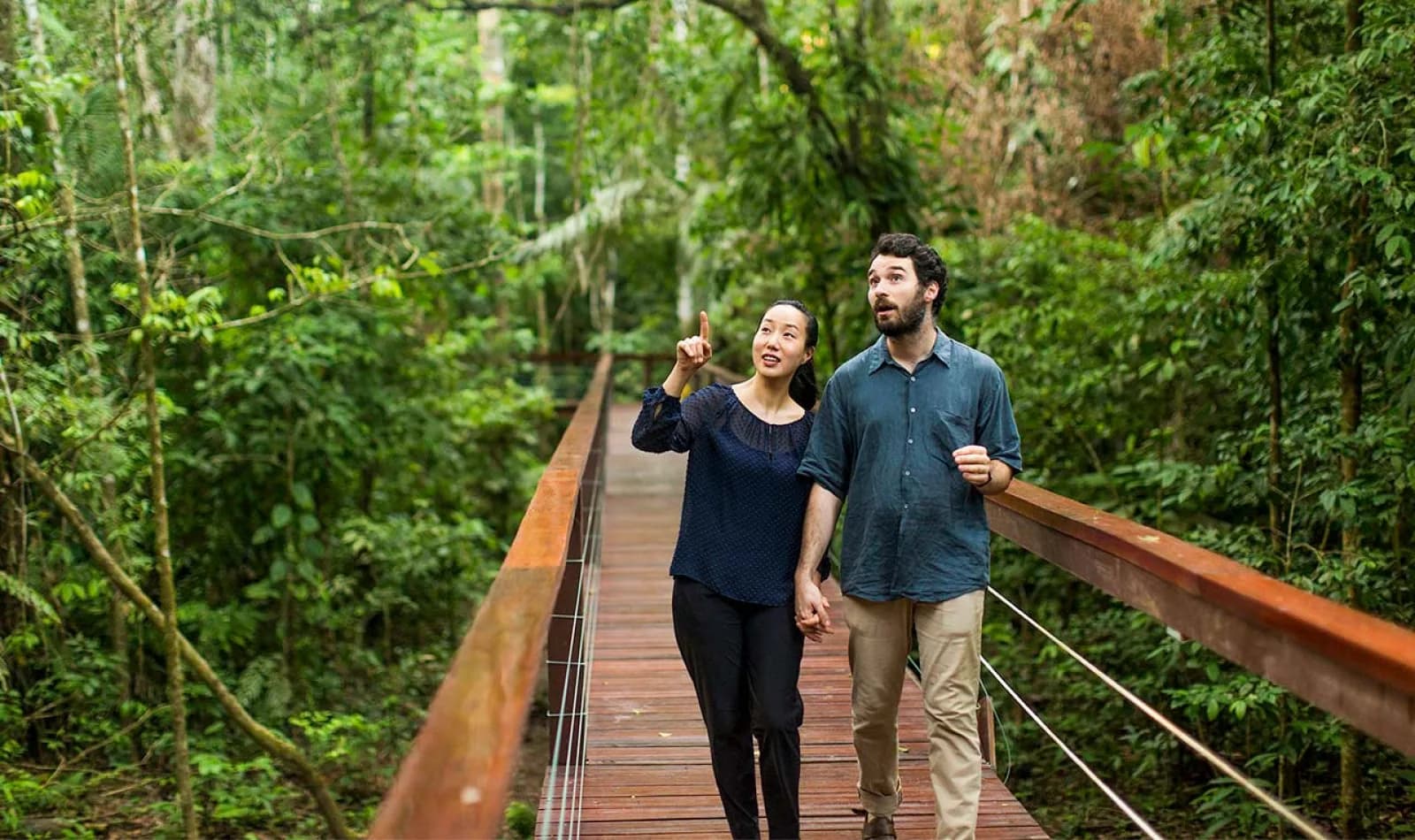 Viajeros caminando por un puente de madera en Tambopata, Perú. 