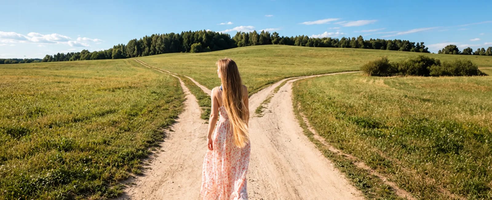 Viajera frente a una bifurcación de caminos en un paisaje rural