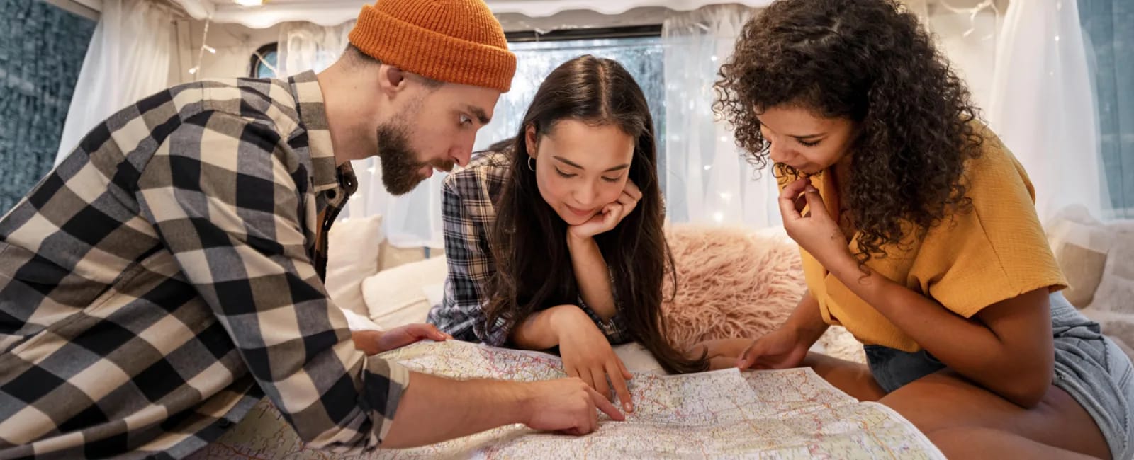 Tres viajeros revisando un mapa y planificando una ruta de viaje en un espacio acogedor