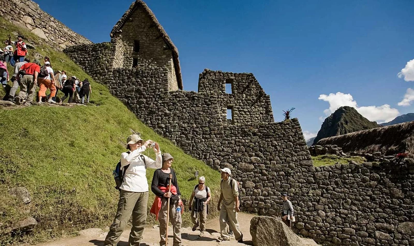 Grupo de turistas tomando fotografías junto a las construcciones de Machu Picchu