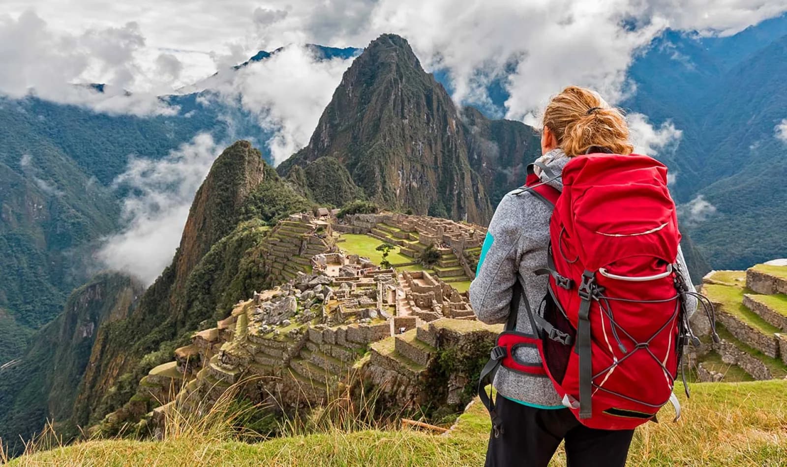 Viajera con una mochila grande roja observando la ciudadela de Machu Picchu