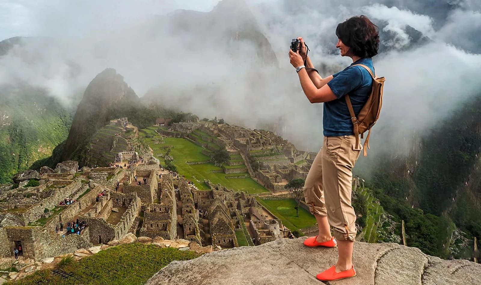 Viajera tomando una fotografía en Machu Picchu, con neblina.