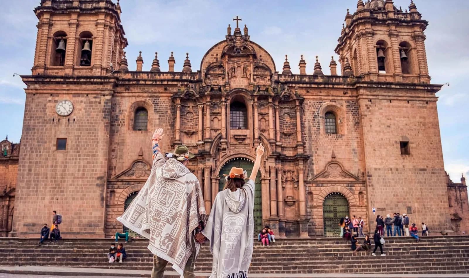 Pareja de viajeros al frente de la catedral en la plaza de armas de Cusco, Perú.