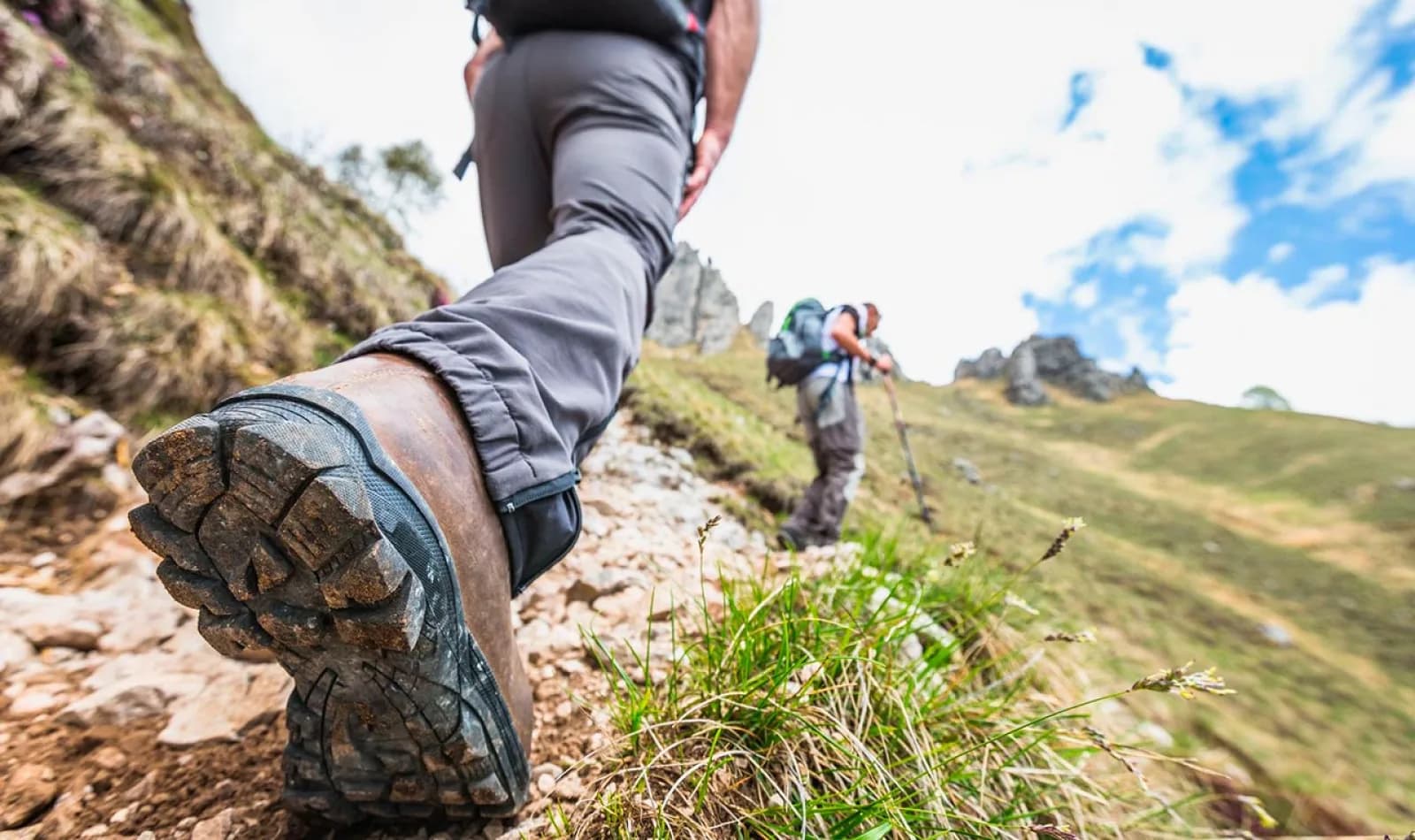 Viajeros haciendo senderismo con zapatillas y bastones de trekking.