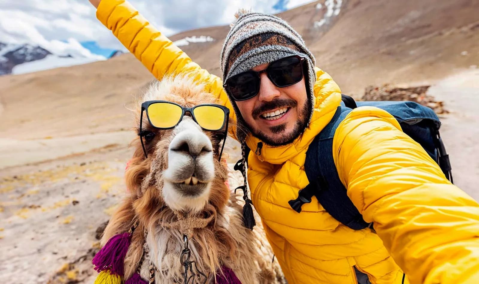Viajero tomándose una selfie con una llama en la montaña de siete colores.