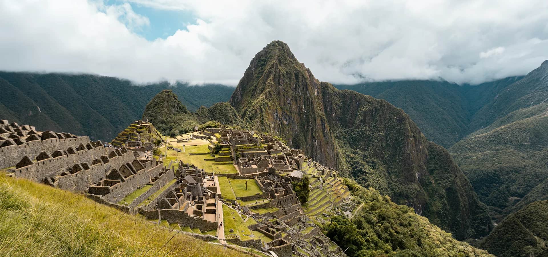 Vista clásica panorámica de Machu Picchu con Huayna Picchu y montañas cubiertas de nubes