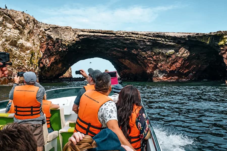 Viajeros en lancha observando formaciones rocosas y aves marinas en las islas Ballestas